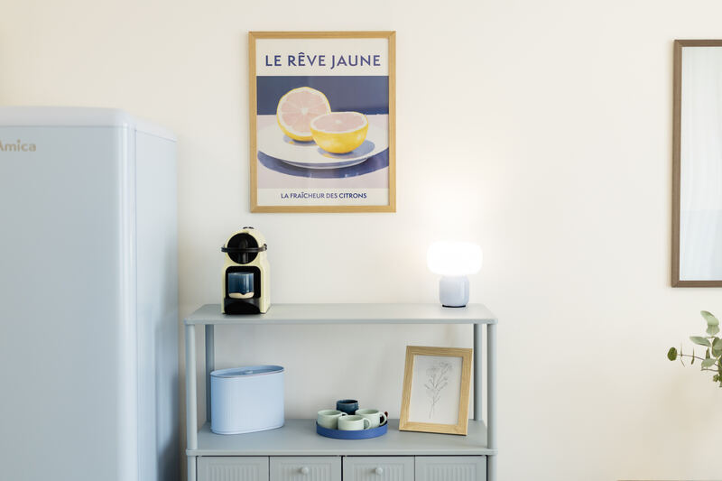 Kávovar a lednice v kuchyňském koutu s designovými plakáty